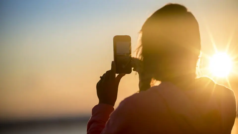 Discrezione: una persona in controluce fotografa il tramonto